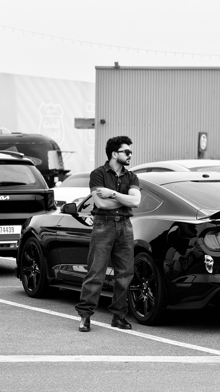 Aadhu standing beside a black Mustang
